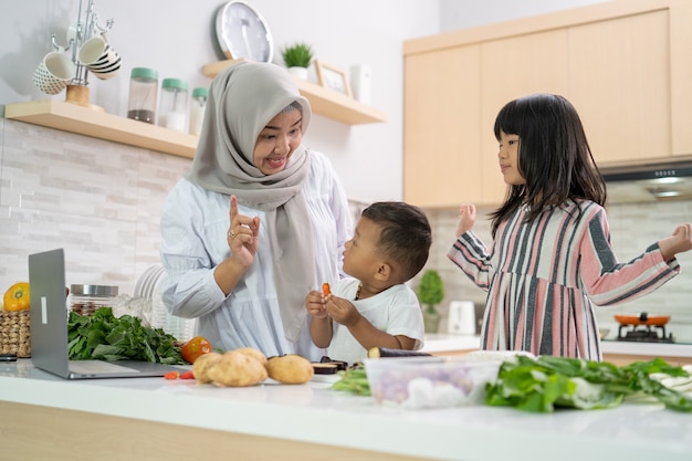 Schöne asiatische Frau mit Tochter und Sohn, die Abendessen während des Ramadan für Iftar kochen, der das Fasten bricht