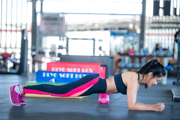 Schöne asiatische Frau spielt Fitness im FitnessstudioThailändisches Mädchen hat einen schlanken KörperZeit für BewegungMenschen lieben HeideDehnung des Körpers vor dem TrainingSportfrau wärmt den Körper aufPush mit Dumbell