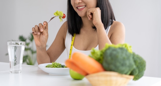 Schöne asiatische Frauen essen gerne Salat, um Gewicht zu verlieren. Gesunde junge Frau, die Gemüsesalat isst. Diäten, gesunde Lebensmittelkonzepte.