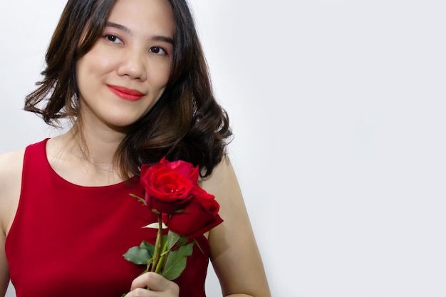 Schöne asiatische Frauen freuen sich über rote Rosen und lächeln und fühlen sich an einem Valentinstag und in der Liebe glücklich.