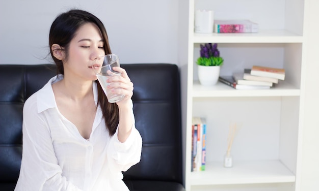 Schöne asiatische Frauen tragen weißes Hemd Trinkwasser für die Haut- und Gesundheitspflege, ein Konzept für einen gesunden Lebensstil.