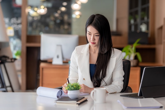 Schöne asiatische Geschäftsfrau, die im Büro arbeitet.