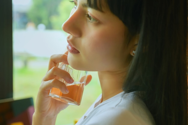 Schöne asiatische junge Frau mit einer Parfümflasche im Haus, Nahaufnahme