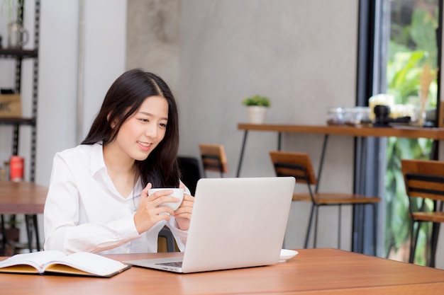 Schöne asiatische junge Geschäftsfrau aufgeregt und vom Erfolg mit Laptop froh.