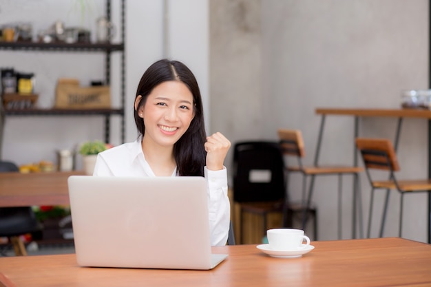 Schöne asiatische junge Geschäftsfrau aufgeregt und vom Erfolg mit Laptop froh.