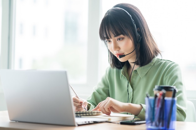 Schöne asiatische Kundendienstdame ruft Kunden an, um Produkte anzubieten