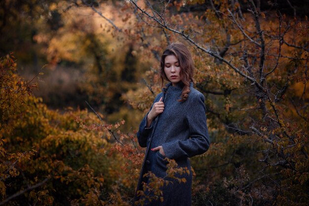 Schöne asiatische Mädchen in grauem Mantel genießen den Herbstwald Die Idee und das Konzept von Spaziergängen an der frischen Luft und Freiheit