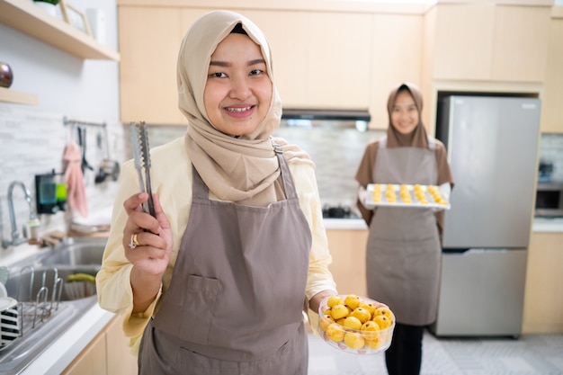 Schöne asiatische muslimische Frau, die zu Hause Nastar-Kuchen für Eid Mubarak macht