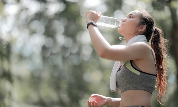 Schöne asiatische Sportlerin Trinkwasser nach dem Training oder Training im Freien, kopieren Raum.