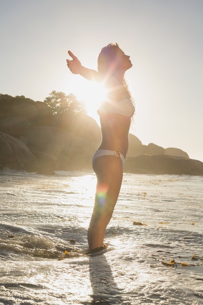 Schöne aufwerfende Blondine im weißen Bikini am Strand