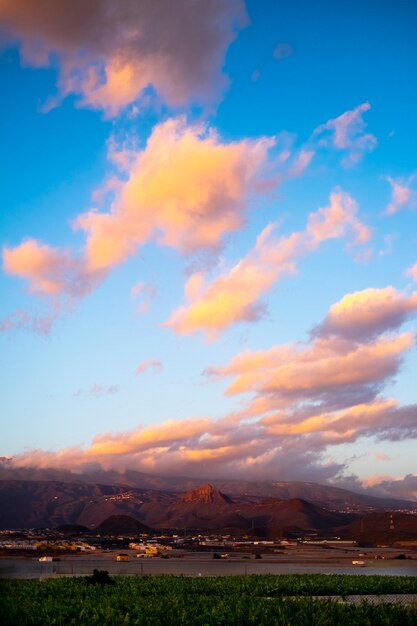 Schöne Aussicht auf Baumbananenplantage und Berge dahinter mit bunten erstaunlichen Wolken am blauen Himmel