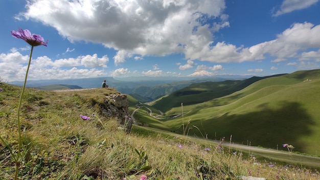 Schöne Aussicht auf Berge und Straße im Kaukasus Russland im Sommer Wanderer sitzt oben