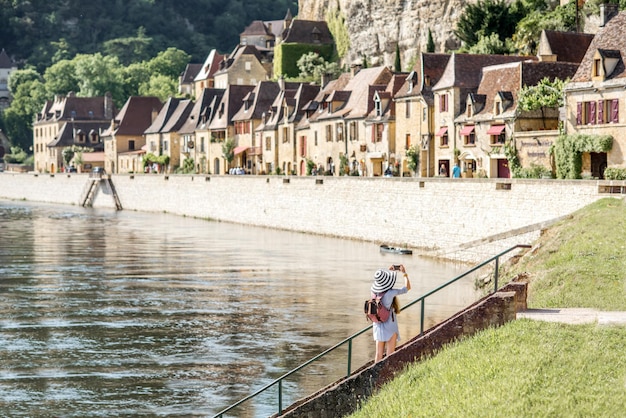 Schöne Aussicht auf das berühmte Dorf La Roque Gageac mit Touristen, die in der Nähe des Flusses in Frankreich stehen?