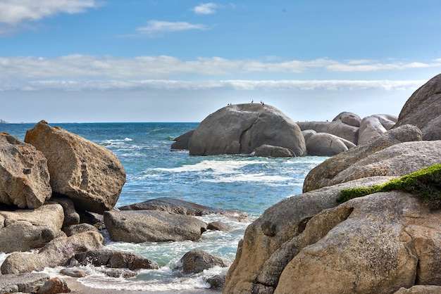 Schöne Aussicht auf das Meer von großen Felsbrocken und Meerwasser an einem sonnigen Strandtag im Sommer Ein Blick auf das Meer der Natur mit einem blauen Himmel, weißen Wolken und Wellen Eine Meereslandschaft in der Nähe der Küste unter dem Horizont