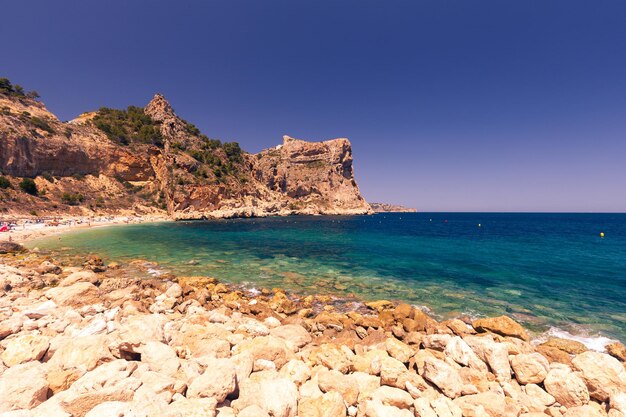 Schöne Aussicht auf den Strand in einer Bucht mit türkisfarbenem Wasser bei Sonnenuntergang La Playa Moraig in Cumbre del Sol Spanien