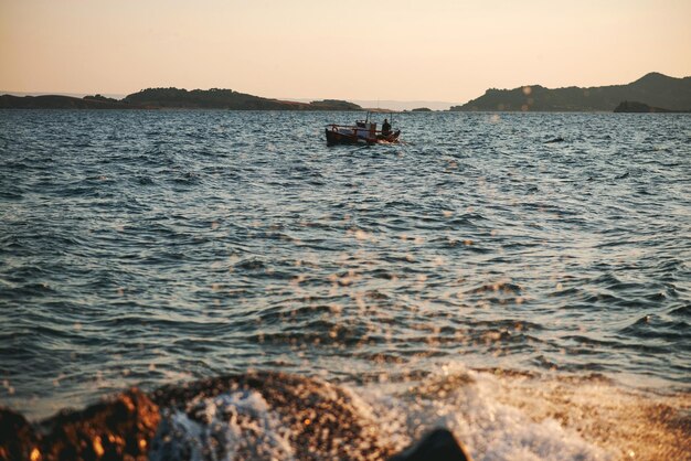 Schöne Aussicht auf ein Segelboot mitten im Meer mit Bergen im Hintergrund bei Sonnenuntergang in der Dämmerung Griechenland