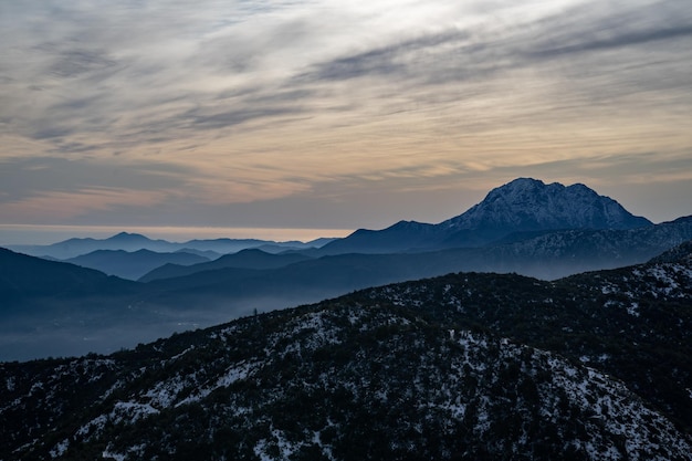 Foto schöne aussicht auf eine verschneite landschaft mit sonnenuntergang und bergen dahinter mit dem hügel la campana