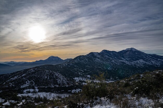 Foto schöne aussicht auf eine verschneite landschaft mit sonnenuntergang und bergen dahinter mit dem hügel la campana