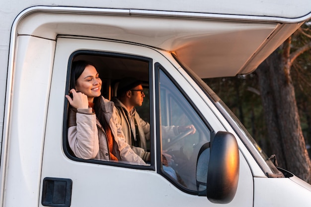 Schöne begeisterte junge Frau, die mit ihrem Auto in den Bergen unterwegs ist, während sie Zeit mit ihrem Ehemann verbringt. Stock Foto