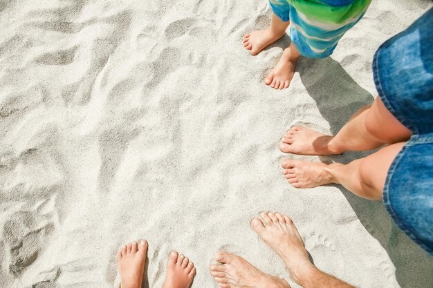 Schöne Beine im Sand des Seegriechenlandhintergrundes