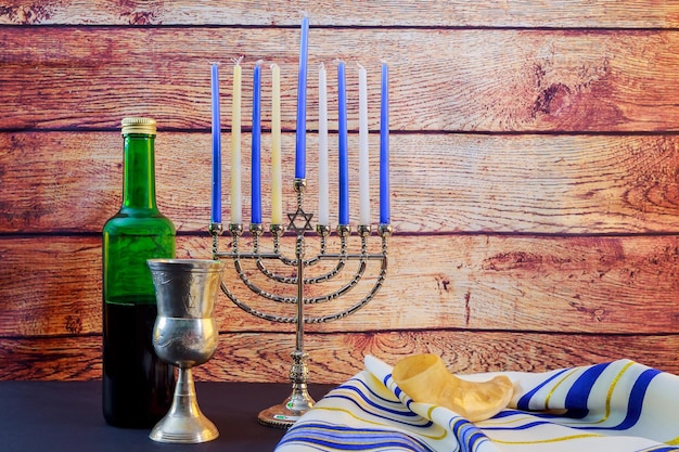 Schöne beleuchtete chanukka-menorah auf schwarzem hintergrund jüdischer feiertag chanukka-wein talyt