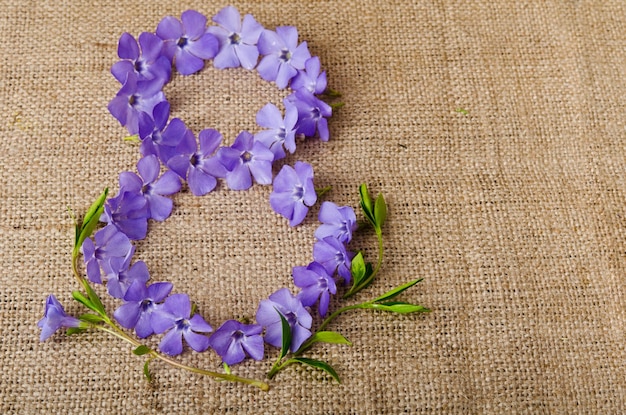 Schöne blaue Blumen in Form einer Acht auf Sackleinenhintergrund