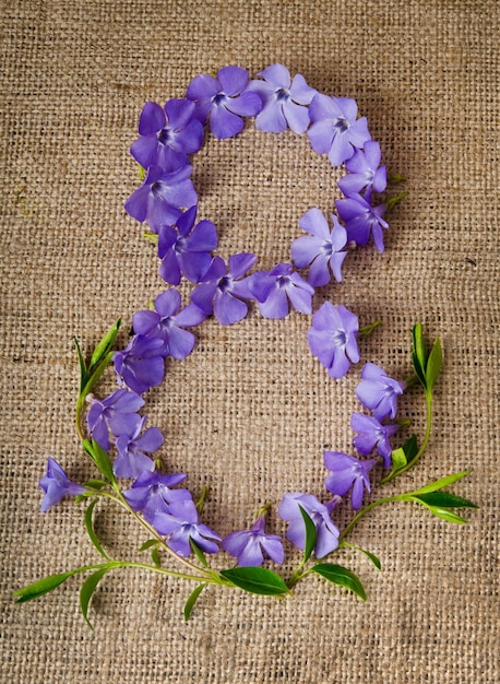 Schöne blaue Blumen in Form einer Acht auf Sackleinenhintergrund