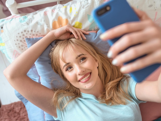 Foto schöne blonde bloggerin macht selfie mit ihrem smartphone