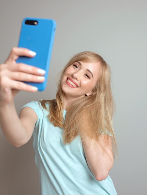 Schöne blonde Bloggerin macht Selfie mit ihrem Smartphone