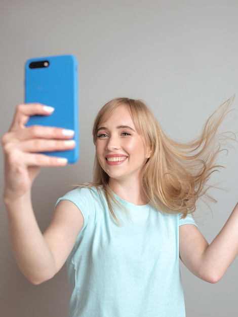 Schöne blonde Bloggerin macht Selfie mit ihrem Smartphone