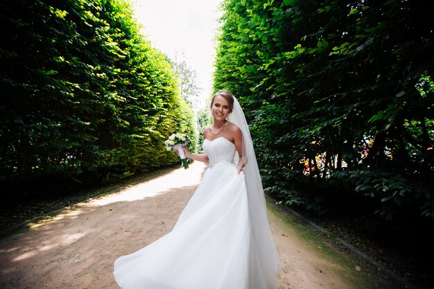 Schöne blonde Braut genießt ihren Hochzeitstag im Sommer