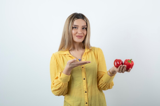 Schöne blonde Frau, die auf rote Paprika zeigt