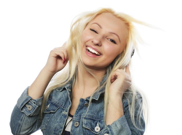 Schöne blonde Frau in den Kopfhörern, die Musik auf Weiß hören