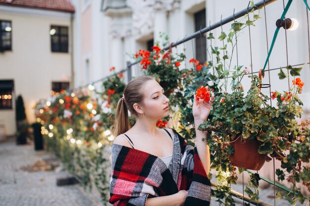 Schöne blonde Frau in einem Blumenhinterhof