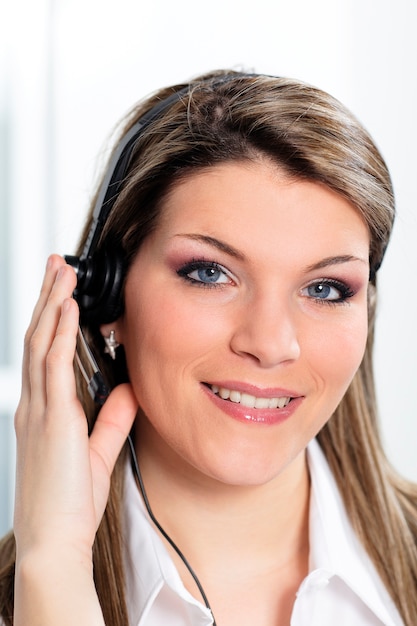 Schöne blonde Frau mit Headset im Büro