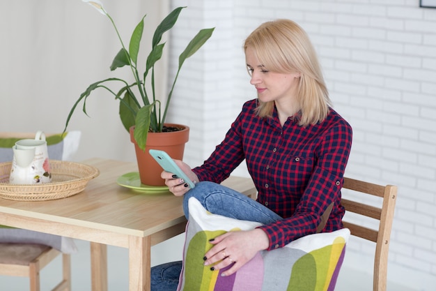 Schöne blonde Frau mit Kissen und Telefon