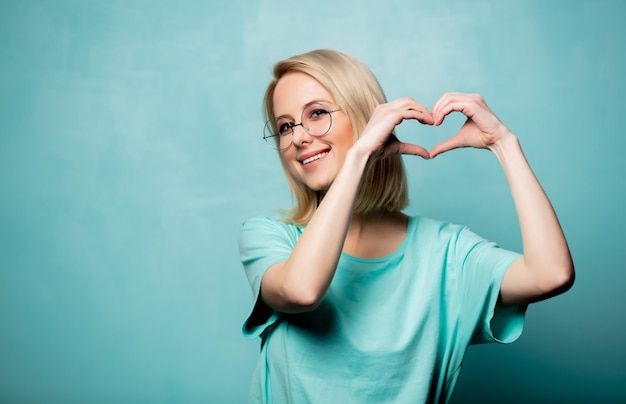 Schöne blonde Frau zeigen Herz in der Hand