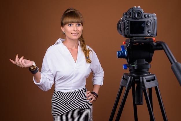 Schöne blonde Geschäftsfrau mit geflochtenem Haar vlogging unter Verwendung der Kamera