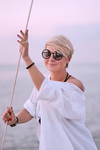 Schöne blonde glückliche Frau, die den Sonnenuntergang auf der Yacht im Meer genießt Reiseabenteuer Entspannung