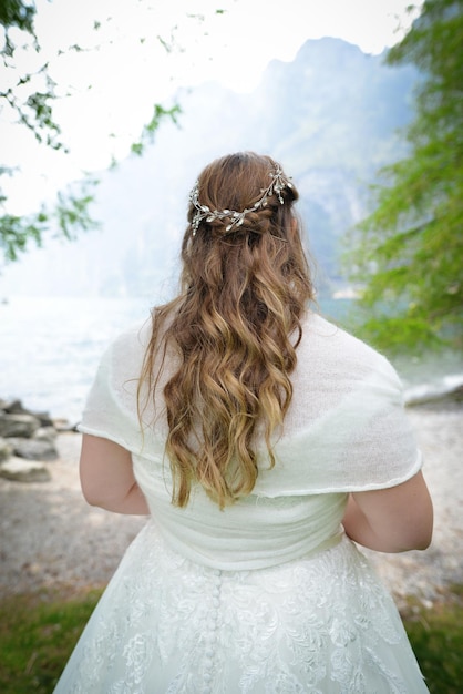 Schöne blonde Haarbraut, die in ihrem Hochzeitskleid im Freien steht