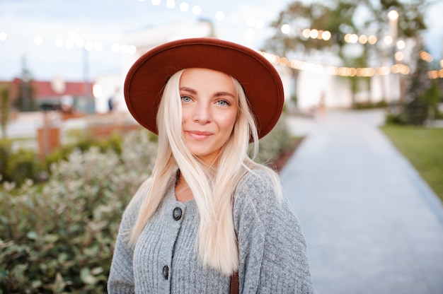 Schöne blonde lächelnde Mädchen tragen Freizeitkleidung und Hut