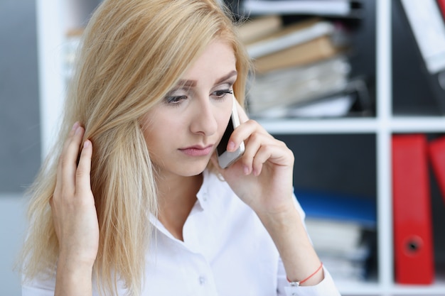 Schöne blonde nachdenkliche Geschäftsfrau sprechen Handy