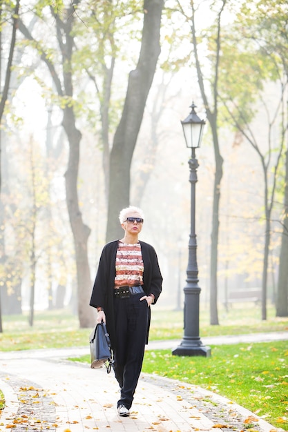 Schöne blonde stilvolle Frau geht in Herbstpark