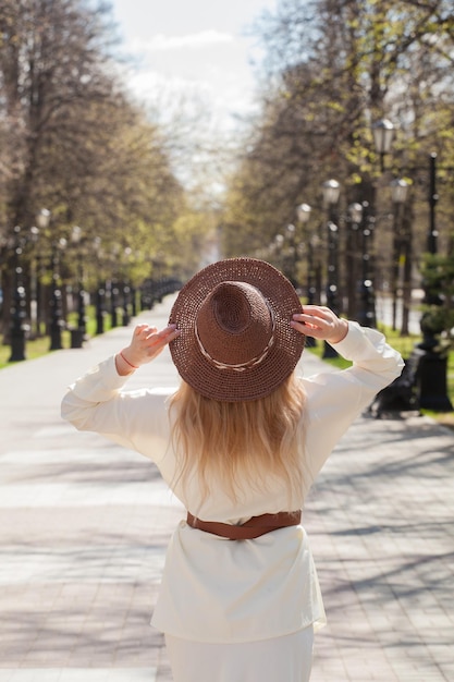Schöne Blondine auf einem Spaziergang in einem Cowboyhut Rückansicht