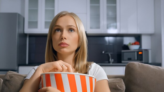 Schöne Blondine, die Popcorn und Film genießt.