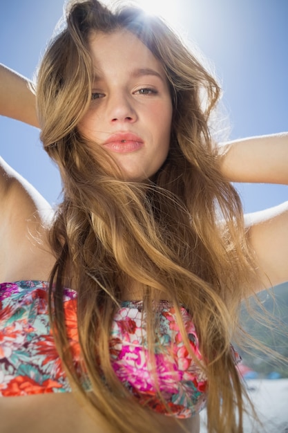 Schöne Blondine im Blumenbikini auf dem Strand