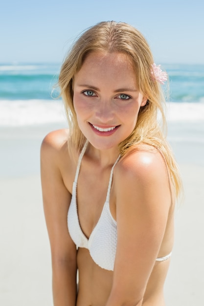 Schöne Blondine im weißen Bikini lächelnd an der Kamera auf dem Strand