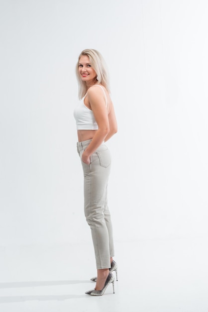 Schöne Blondine in Jeans im Studio auf hellem Hintergrund.