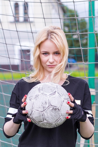 Foto schöne blondine mit einem ball am fußballtor