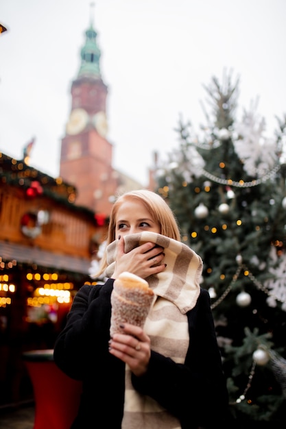 Schöne Blondine mit Spuckenkuchen am Weihnachtsmarkt in Breslau, Polen